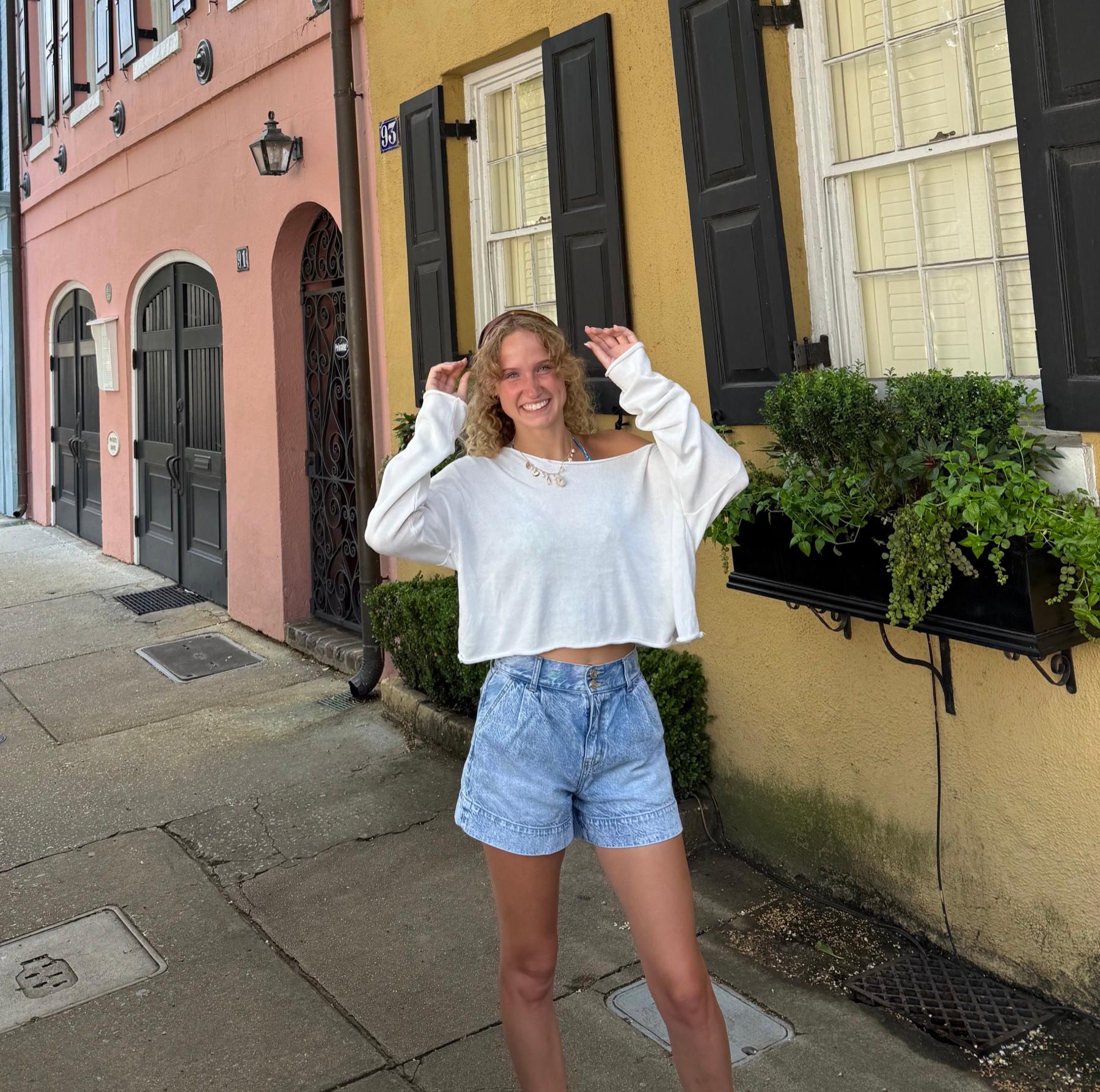 Brekyn Kok on a colorful street, smiling with her hands in her hair